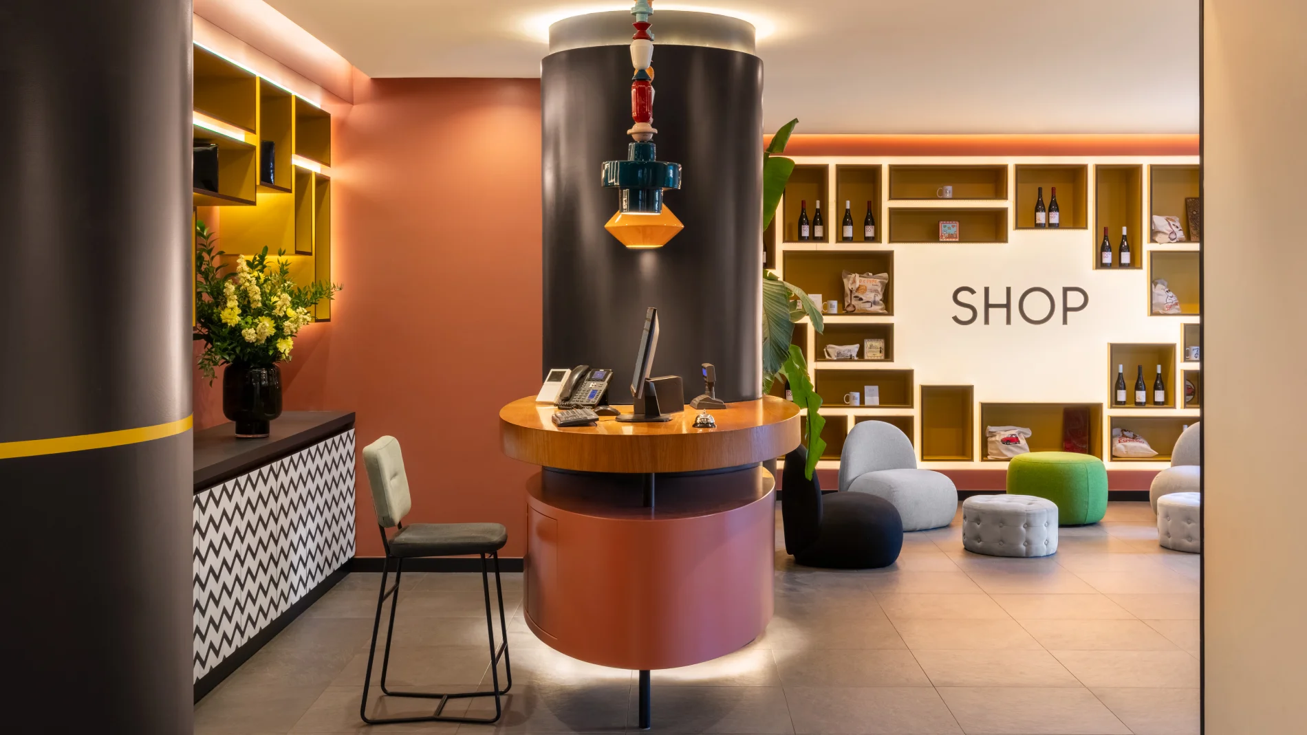 Modern reception with in-house shop, illuminated shelves and colorful guest lounge area - Aparthotel Colombo, BZAR hotels in Rome