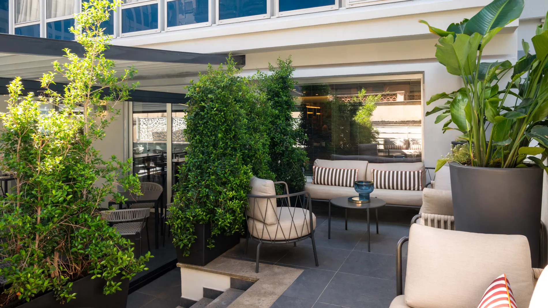 Outdoor patio with sofas, armchairs and lush plants for relaxing open-air moments - Aparthotel Colombo, BZAR hotels in Rome