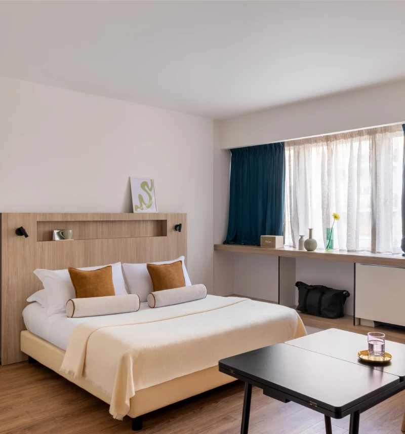 Spacious room with double bed, black coffee table, wide window and mustard accents - Aparthotel Colombo, BZAR hotels in Rome