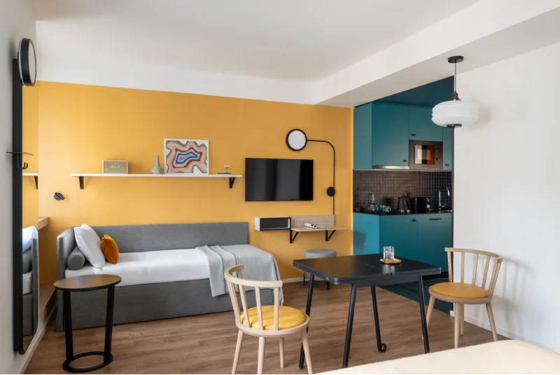 Studio apartment with sofa bed, turquoise kitchen, black table and mustard wall for long stays - Aparthotel Colombo, BZAR hotels in Rome